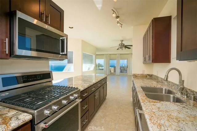 a kitchen with kitchen island granite countertop a sink stainless steel appliances and cabinets