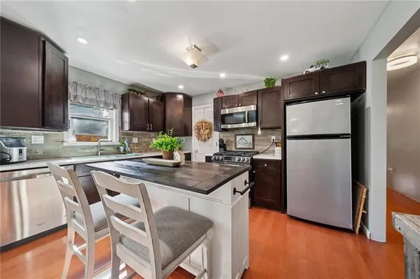 a kitchen with kitchen island granite countertop wooden cabinets and refrigerator