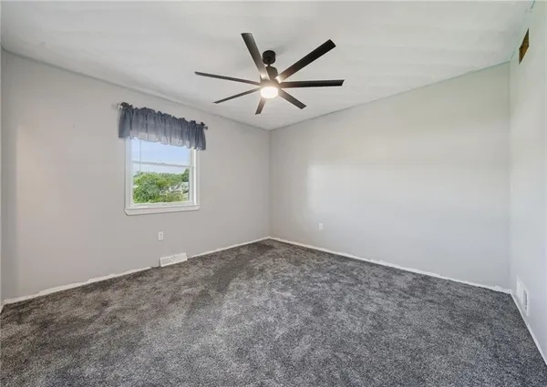 an empty room with windows and ceiling fan