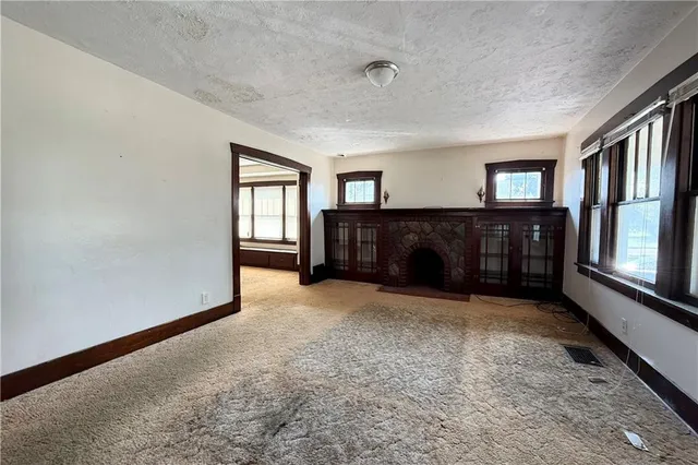 a view of an empty room with window and fireplace