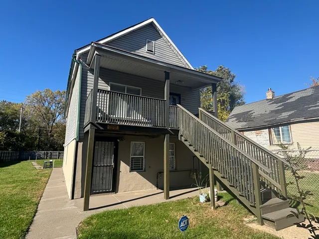 a view of house with wooden stairs and a small yard