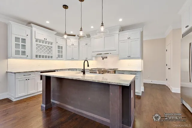 a kitchen with kitchen island granite countertop a sink a center island and wooden floor