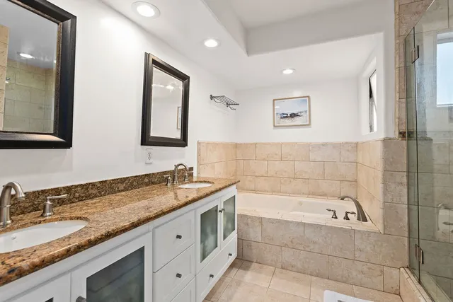 a bathroom with a granite countertop tub sink and mirror