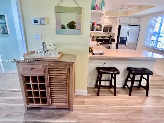 a view of kitchen with stainless steel appliances kitchen island granite countertop dining room and chairs
