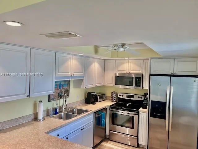 a kitchen with stainless steel appliances granite countertop a sink a stove and a refrigerator
