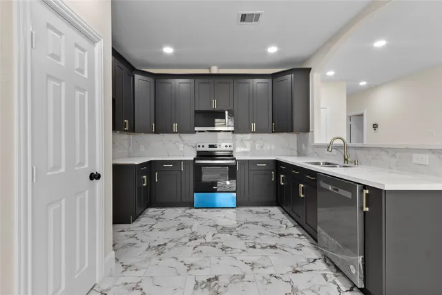 a kitchen with kitchen island granite countertop a refrigerator stove top oven and sink