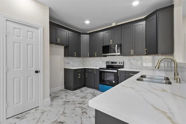 a kitchen with granite countertop a refrigerator stove top oven and sink