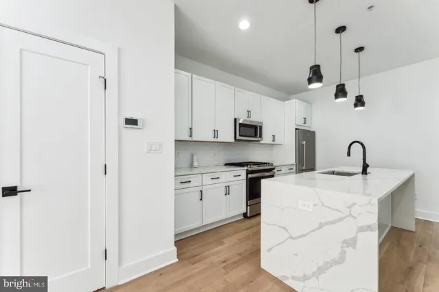 a kitchen with stainless steel appliances kitchen island a white cabinets a sink a stove and a refrigerator