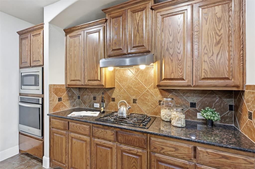 2841 Meadow Ridge Drive Prosper, TX 75078 - Photo 14 of 40 a kitchen with stainless steel appliances granite countertop white cabinets and a refrigerator