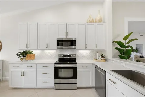 a kitchen with white cabinets and appliances