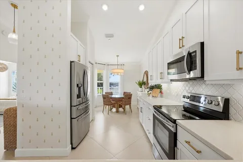 a kitchen with stainless steel appliances a refrigerator a stove top oven a sink dishwasher and white cabinets