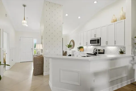 a kitchen with stainless steel appliances a sink a stove a microwave a refrigerator a white table and chairs