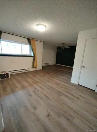a view of an empty room with wooden floor and windows