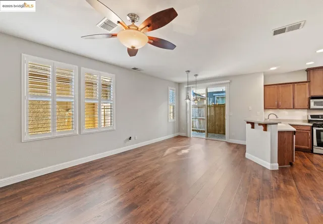 a view of an empty room with a kitchen and wooden floor