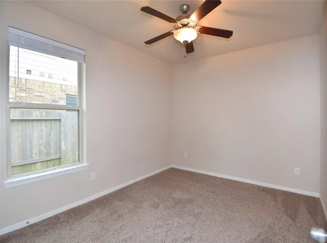 an empty room with a window and a fan