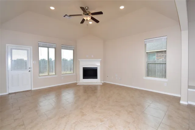 a view of an empty room with a window and a kitchen