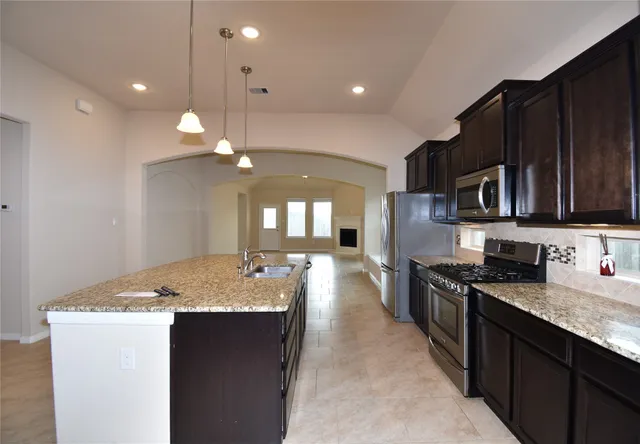 a kitchen with stainless steel appliances granite countertop a sink stove and refrigerator