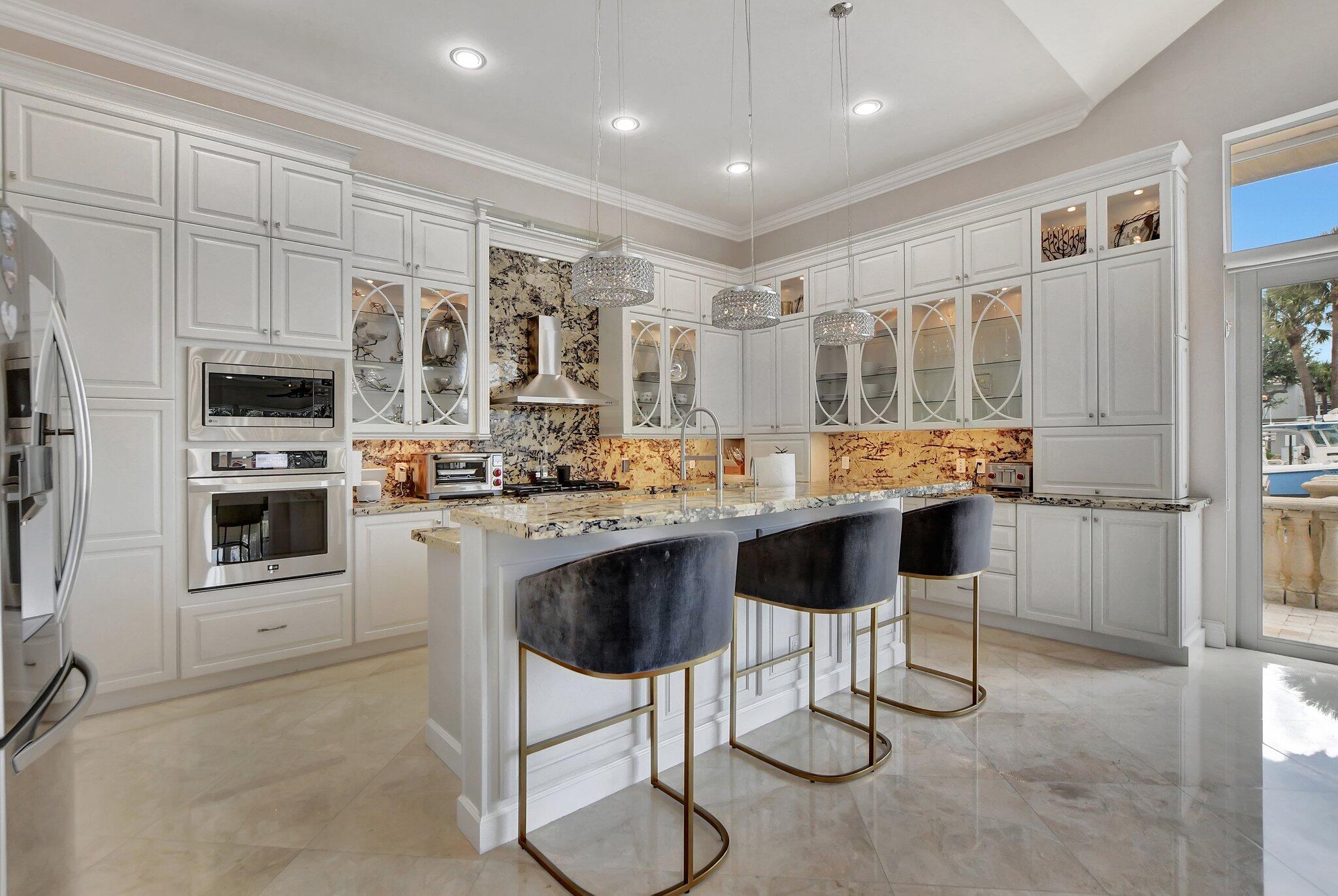 857 Havana Drive Boca Raton, FL 33487 - Photo 7 of 30 a kitchen with stainless steel appliances kitchen island granite countertop a stove top oven a sink a dining table and chairs