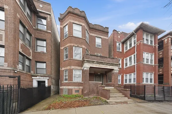 a front view of a brick building next to a yard