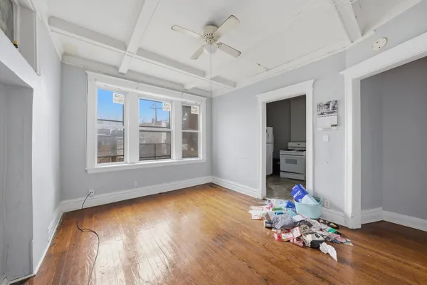 a view of an empty room with wooden floor and a window