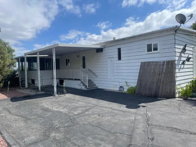a backyard of a house with table and chairs under an umbrella