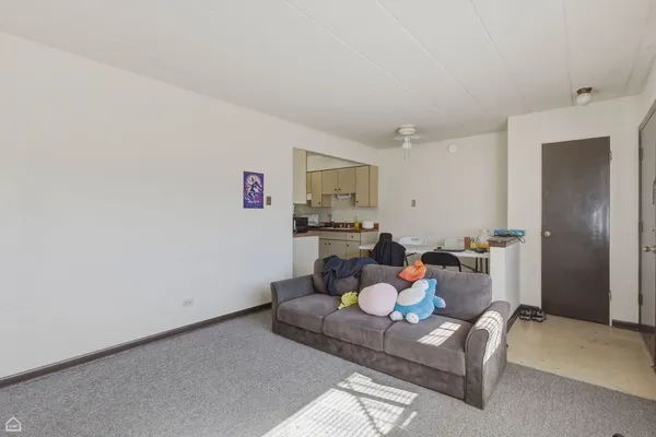 a living room with furniture and a refrigerator