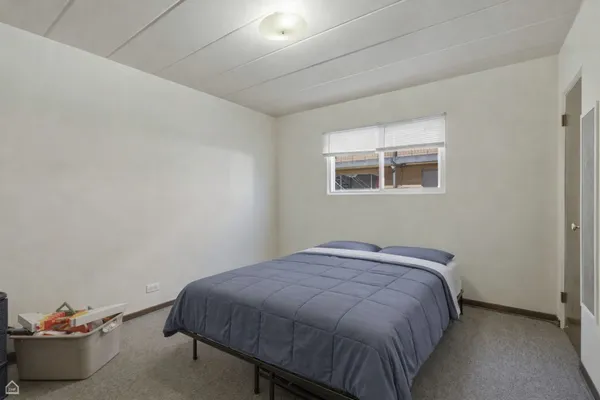 a bed sitting in a bedroom next to a window and a potted plant