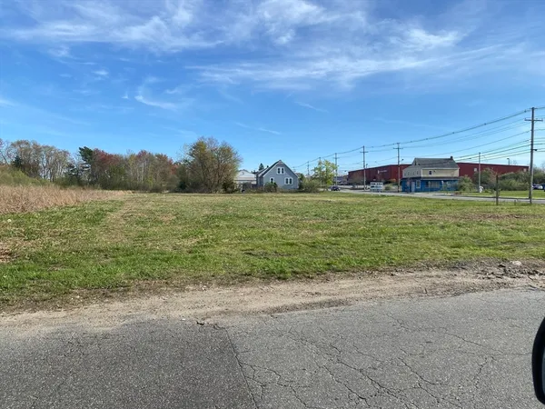 a view of a field with an ocean and trees