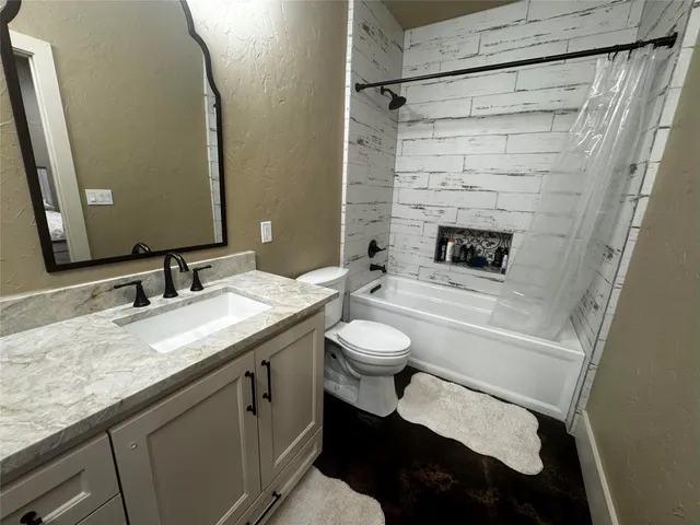 a bathroom with a granite countertop sink toilet and shower
