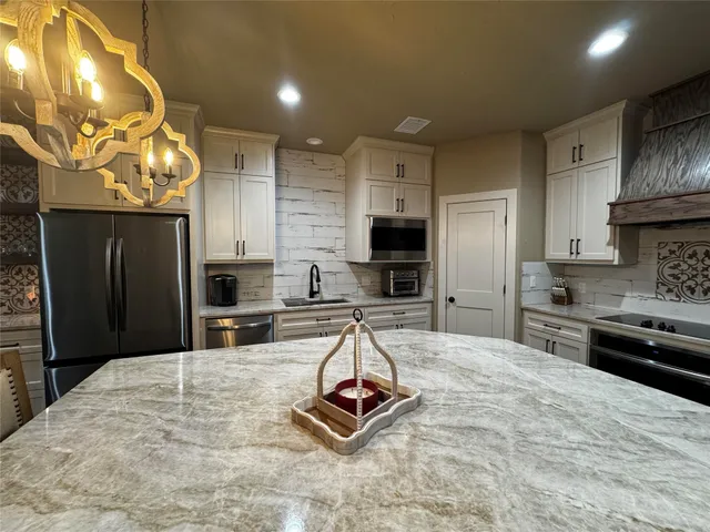a kitchen with kitchen island granite countertop a stove refrigerator and cabinets
