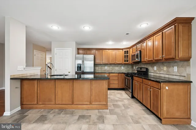 a large kitchen with stainless steel appliances granite countertop a stove top oven a sink dishwasher and cabinets with wooden floor