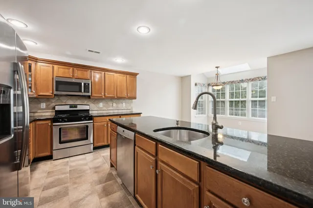 a kitchen with granite countertop a sink and stainless steel appliances