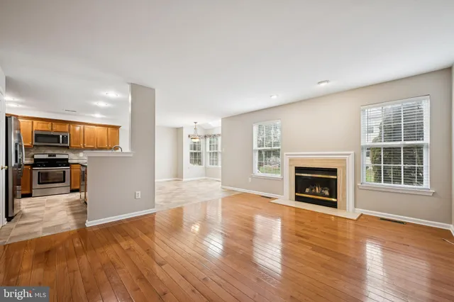 an empty room with wooden floor a fireplace and window