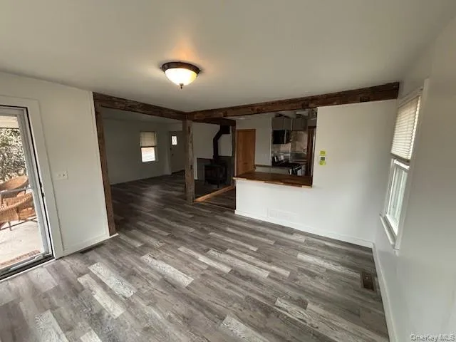 a view of a refrigerator in kitchen and an empty room with wooden floor and a window
