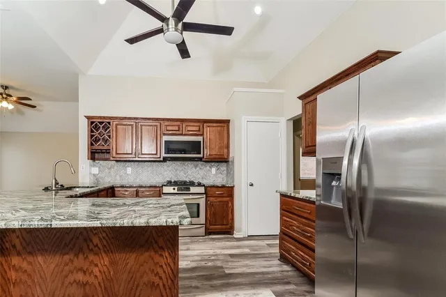 a kitchen with kitchen island granite countertop a refrigerator a sink and a stove