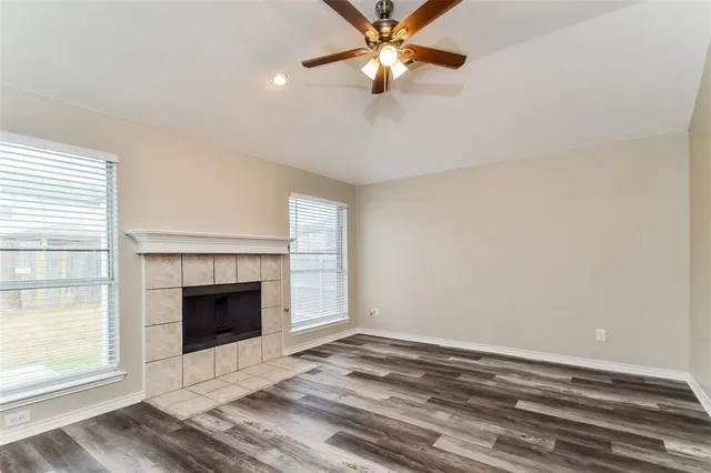 an empty room with fireplace fan and windows