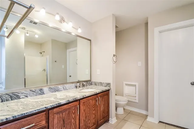 a bathroom with a granite countertop sink a toilet and a large mirror