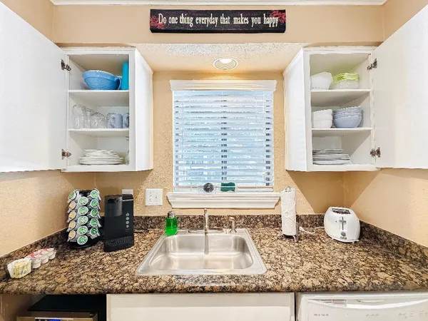 a kitchen with a granite countertop sink and a window