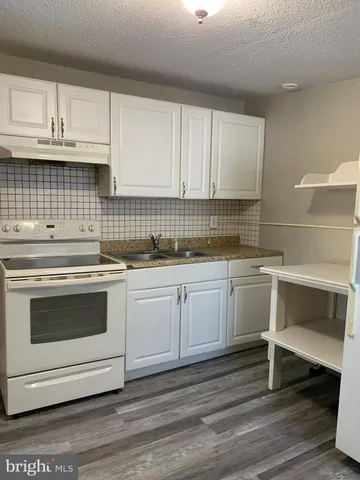 a kitchen with granite countertop white cabinets and white appliances