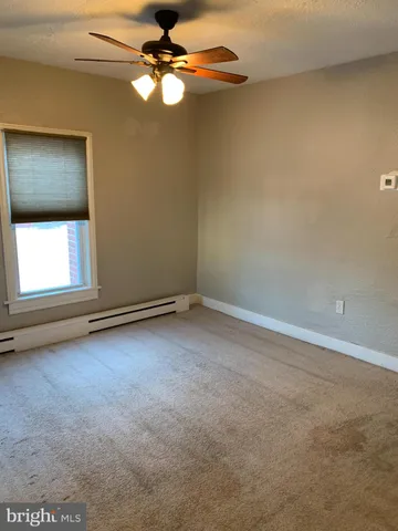 an empty room with a window and ceiling fan