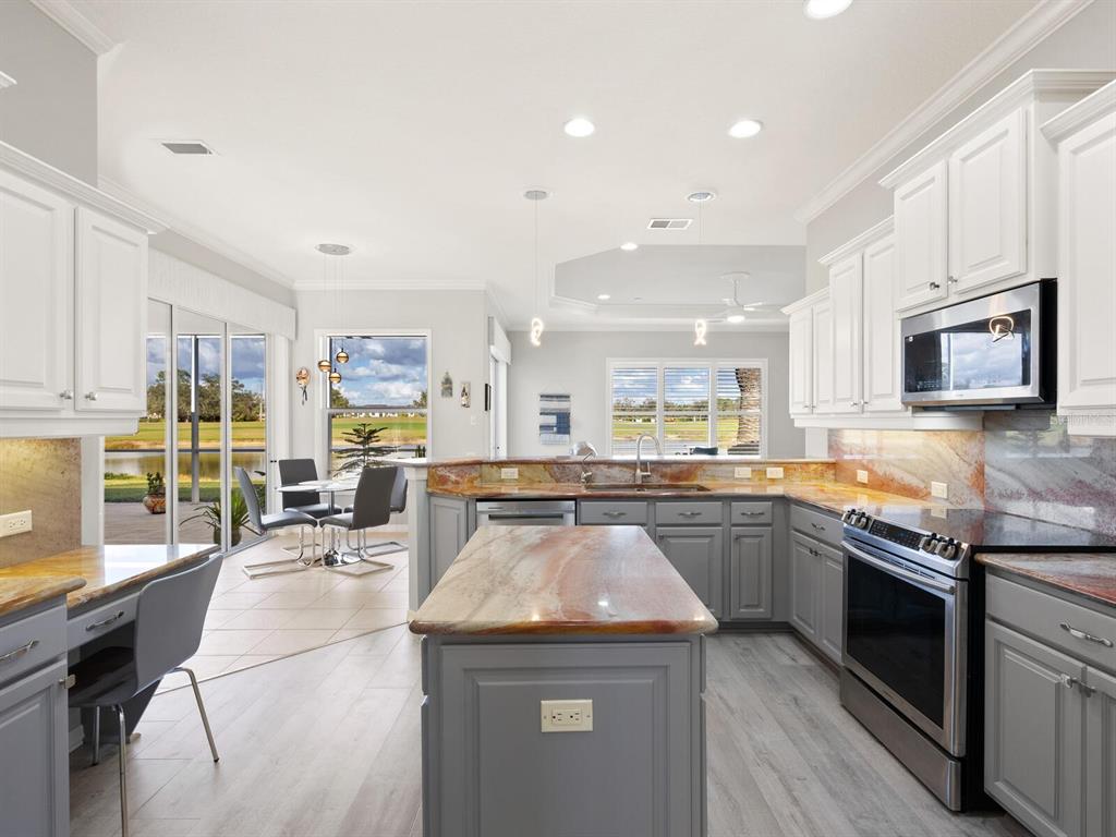 814 Adonis Place Venice, FL 34292 - Photo 18 of 38 a kitchen with stainless steel appliances granite countertop stove top oven and cabinets