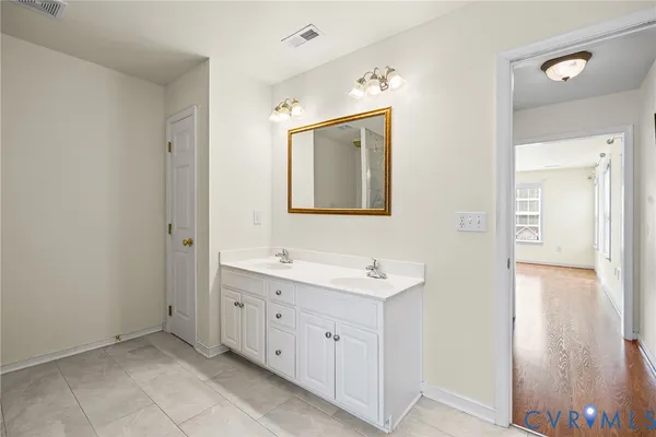 a spacious bathroom with a double vanity sink a mirror and a