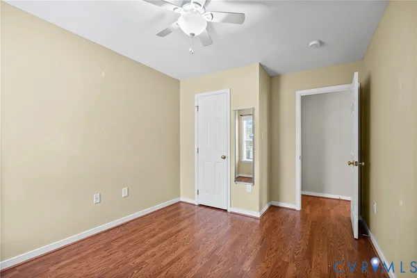 an empty room with wooden floor and chandelier fan