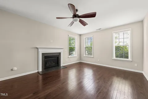 an empty room with wooden floor a ceiling fan and windows