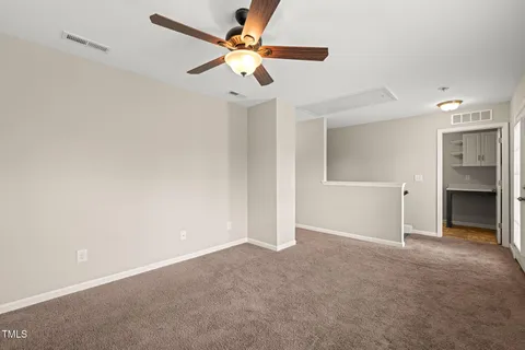 an empty room with chandelier fan and windows