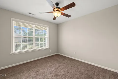 an empty room with ceiling fan and window