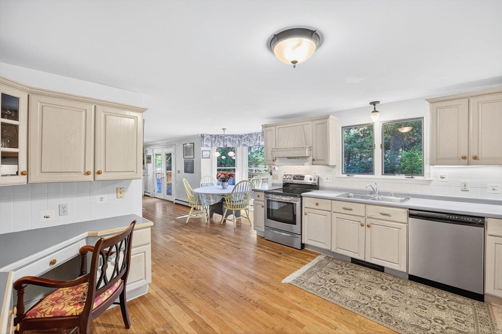 36 Tar Kiln Road Orleans, MA 02653 - Photo 9 of 42 a kitchen with stainless steel appliances granite countertop a stove top oven a sink a dining table and chairs with wooden floor