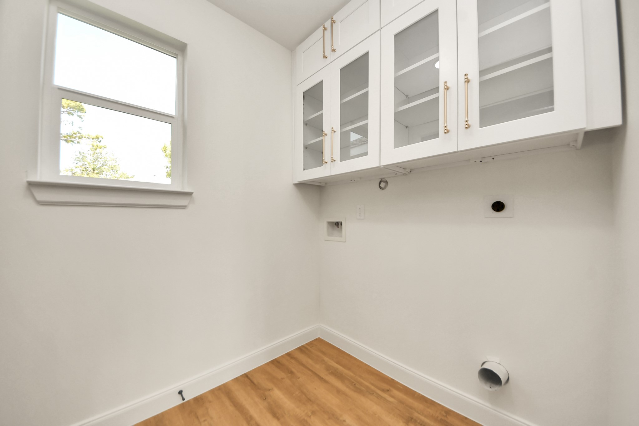 1737 Tabor Street Houston, TX 77009 - Photo 23 of 46 This bright laundry room features white cabinetry with glass doors, and a window for natural light. It has hookups for a washer and dryer.