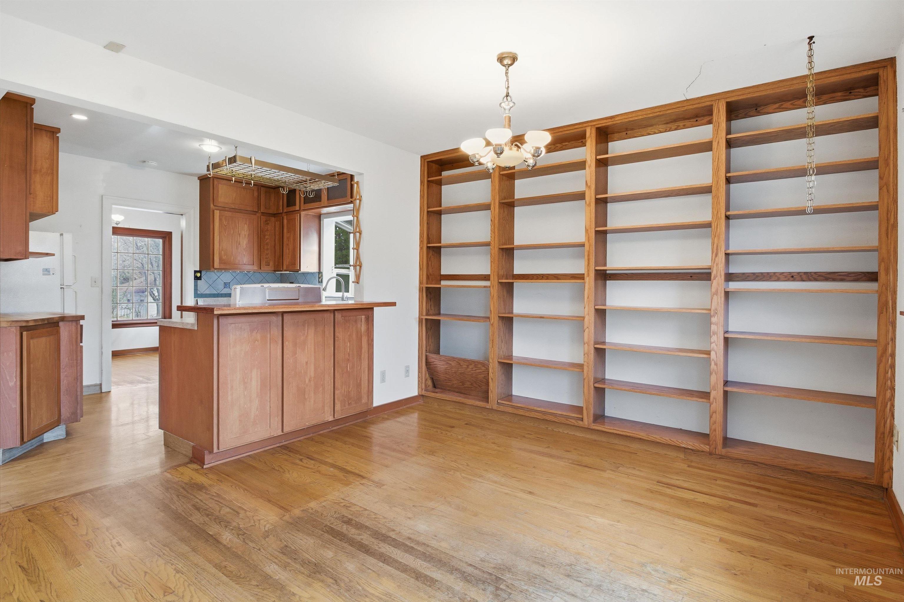 1117 East 6th Street Moscow, ID 83843 - Photo 11 of 46 Kitchen with wood finish cabinetry, suspended lighting, a peninsula, light wood-style flooring, and freestanding refrigerator