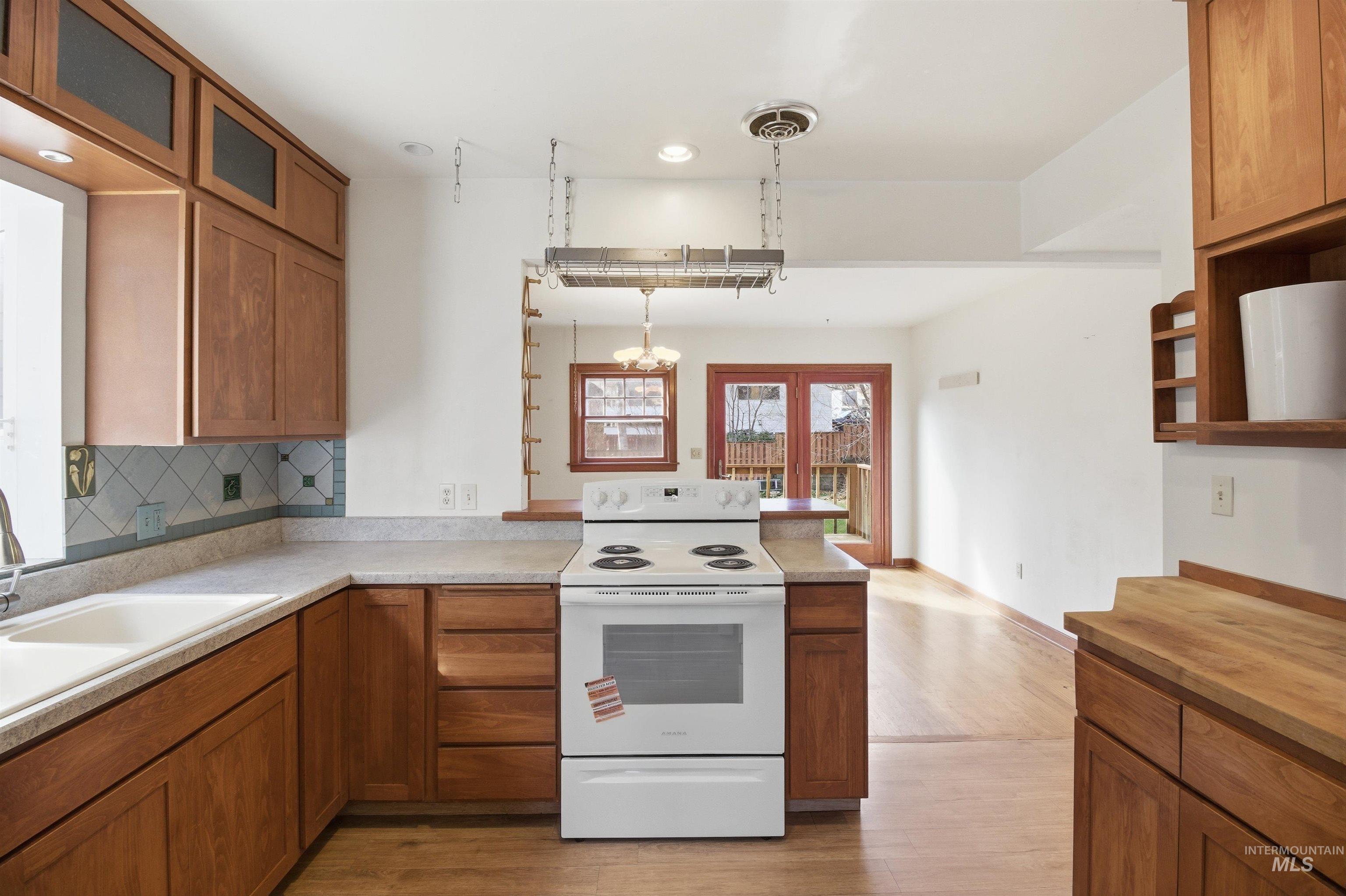 1117 East 6th Street Moscow, ID 83843 - Photo 16 of 46 Kitchen with wood finish cabinets, white range with electric cooktop, and a peninsula
